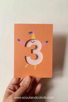 someone is holding up a card with the number 3 on it and an orange background