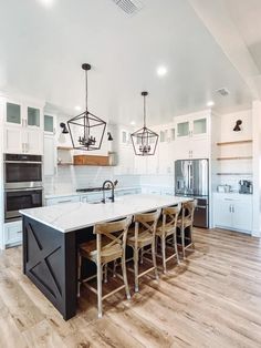 a large kitchen with white cabinets and an island in the middle, surrounded by wooden flooring