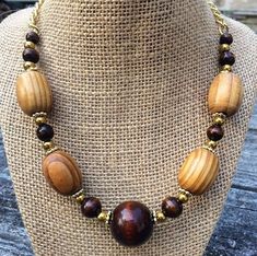 This elegant, one of a kind necklace is made up of real wood- stained light and dark - and painted gold beads. The beads are all tied securely to a gold chain which fastens easily behind the neck with a toggle clasp. The necklace measures around 18 inches long. Wood Beads Necklace Ideas, Brown Wooden Beaded Jewelry, Beaded Natural Wood Jewelry, Brown Wooden Necklace With Large Beads, Natural Wood Beaded Jewelry, Wooden Large Beads Jewelry As Gift, Adjustable Gold Beaded Necklaces With Wooden Beads, Adjustable Gold Beaded Necklace With Wooden Beads, Gold Beaded Necklaces With Wooden Beads