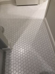 a bathroom with white tile and hexagonal pattern on the floor