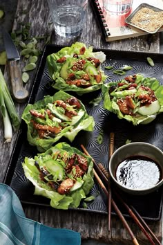 lettuce wraps with meat and vegetables on a tray next to chopsticks