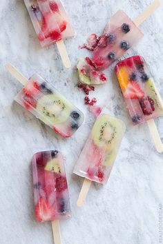 four popsicles with fruit on them sitting on a marble surface