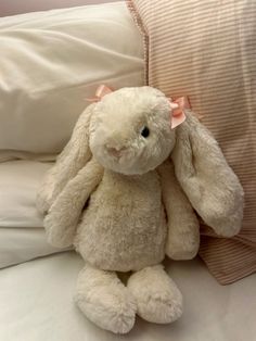 a white stuffed rabbit sitting on top of a bed