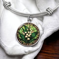 Lily of the Valley Bracelet, A personalized gold floral charm pendant, adorned with delicate Lily of the Valley flowers. The perfect May birth month flower jewelry for a heartfelt Valentine's, Birthday Day or Mother's Day gift. ➜ Our Lily Of The Valley Jewelry is made of high quality surgical steel with a graphic image that's printed directly onto the steel surface with a shatterproof liquid glass coating and includes an 18k gold finish option. ➜ Our Engraved Lily Of The Valley Pendant Bracelet Mother's Day Green Flower Jewelry, Flower Charm Jewelry For May Birthstone, Flower Jewelry With May Birthstone Charm, Flower-shaped Jewelry With Flower Charm For May Birthstone, May Birthstone Jewelry With Flower Charm, Flower-shaped Bracelets With Charms For Gift, Green Bracelet With Flower Charm As Gift, Metal Bracelet With Flower Charm As Gift, Green Birth Flower Round Jewelry