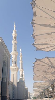 an outdoor area with umbrellas and white buildings in the background on a sunny day