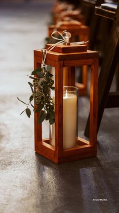 a candle is sitting in a wooden lantern with a plant on the front and side