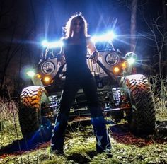 a woman standing in front of a four - wheeler with lights on it's headlights