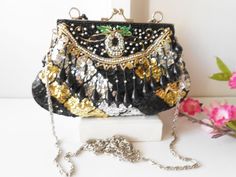 "A glamorous vintage beaded evening bag. Wow, this bag sparkles! The background is black taffeta and it is covered with black, silver and gold sequins and beads. The bag has a silvertone frame and a kiss lock. The interior of the bag is black taffeta and it contains one small pocket. This bag is versatile as it has both a short bead handle plus a chain strap to wear on you shoulder or cross body. This is such a glamorous evening bag. MATERIAL: Beads, sequins, taffeta CONDITION: It is in very goo Rectangular Sequin Bag For Evening, Rectangular Sequined Evening Bag, Rectangular Sequin Evening Bag, Black Embellished Evening Bag As Gift, Black Embellished Evening Bag For Gift, Black Embellished Pouch Evening Bag, Party Black Clutch With Sequins, Black Evening Bags With Sequins, Evening Handheld Sequin Bag