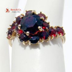 Dazzling 18K Yellow Gold Garnet Studded Cocktail Ring. The Garnets are round brilliant cut. This wonderful ring is a size 6 1/2 and weighs 3g. The larger Garnet measures 7mm in diameter and the smaller Garnets are 4mm in diameter. [nb457] Fine Jewelry Garnet Cluster Ring, Fine Jewelry Round Cluster Ring With Garnet, Red Cluster Ring Stamped 14k, Red 14k Stamped Cluster Ring, Formal Round Garnet Cluster Ring, Round Garnet Cluster Ring For Anniversary, Heirloom Style Round Garnet Cluster Ring, Heirloom Style Garnet Cluster Ring, Heirloom Garnet Cluster Ring