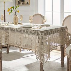 a dining room table with white chairs and a lace doily on the tablecloth