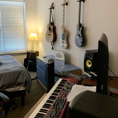 a bedroom with guitars hanging on the wall and a keyboard in front of a bed