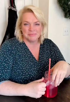 a woman sitting at a table with a drink