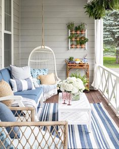 the porch is decorated with blue and white striped rugs, wicker furniture, and hanging planters