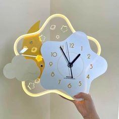 a person holding up a clock with clouds and stars on it