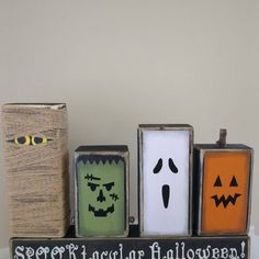 three wooden blocks with faces and words painted on them