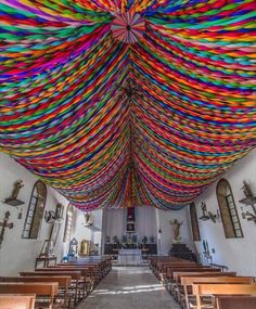 the inside of a church with colorful ribbons hanging from the ceiling