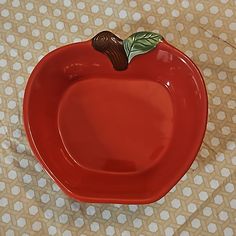 a red apple shaped dish with a leaf on it