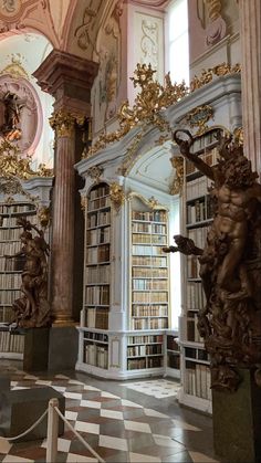 there are many bookshelves and statues in this room with marble flooring on the walls