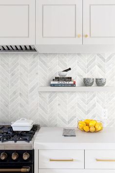 a kitchen with white cabinets and yellow fruit on the counter top, along with an oven