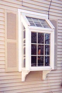 a window on the side of a house with shutters open and a cat looking out