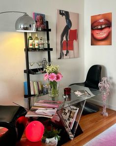 a living room with a glass table and black chairs next to a shelf filled with books