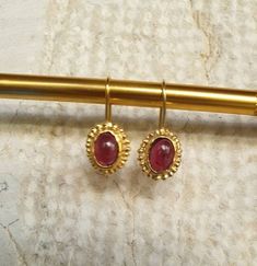 14k gold earrings, Garnet earrings, January birthstone earrings, Antique inspired earrings, vintage earrings, Red oval earrings These antique inspired red Garnet earrings were 100% handmade. The see through wine red Garnet stones are just beautiful and shine softly against the gold contour of the earrings. These January Birthstone earrings are just the perfect gift for yourself or someone you love. They can be great gold bridal earrings. Dimensions: The earrings drop length is 2.5cm or 1 inch Th Vintage Gold Gemstone Earrings, Elegant Gold Garnet Cabochon Jewelry, Oval Garnet Gemstone Earrings, Gold Brass Earrings With Cabochon Detail, Gold Cabochon Brass Earrings, Gold Brass Cabochon Earrings, Elegant Gold Garnet Earrings, 14k Gold Cabochon Earrings Gift, Heirloom Oval Gold Earrings