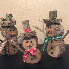 three snowmen made out of wood with hats and scarfs