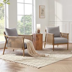 a living room with two chairs and a rug in front of the window, next to a fireplace