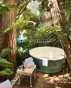 a bath tub sitting on top of a wooden floor next to a lush green forest