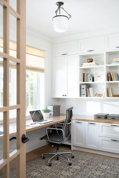 an image of a home office with white cabinets and drawers on the left side of the room