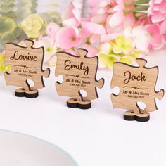 three personalized wooden puzzle pieces on a table with flowers in the backgroud