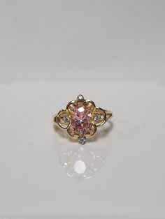 "Thanks for shopping our vintage estate store. We tend to sell well below wholesale and truly hope you enjoy all of our items. Many of the items are one of a kind, so please enjoy scrolling through the pictures and hopefully something will catch your eye. Brown spots are from camera or reflections. Estate 10k yellow gold created pink 1.5ct ice cz diamond filigree cocktail ring.  White gems are cz diamonds also.  Ring size: 5.75 Gem: 8mm by 5mm Setting: 1/2\"  Band Width: 1.5mm Weight: 2.70 grams Sweet ring, one that you will love. Marked 10K." Classic Pink Cluster Ring For Anniversary, Vintage 14k Gold Birthstone Ring With Center Stone, Vintage Diamond Birthstone Ring, Hallmarked, Vintage Diamond Birthstone Ring Hallmarked, Vintage Oval Diamond Ring With Vs Clarity, Vintage Pink Diamond Ring Hallmarked, Vintage Pink Diamond Ring With Hallmark, Vintage Hallmarked Birthstone Ring With Round Cut, Vintage Yellow Gold Cluster Ring With Accent Stones