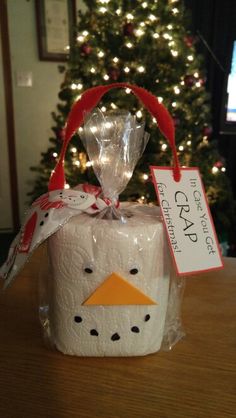 a gift wrapped in plastic sitting on top of a table next to a christmas tree