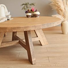 a wooden table sitting on top of a hard wood floor next to a vase filled with flowers