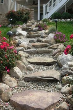 a stone path leading to a house with flowers in the foreground and stairs on either side