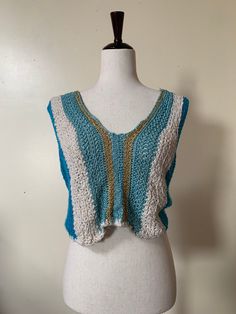 70s Vintage Knit Crop Top Super cute boho style 1970s knit crop top. Comfy sleeveless tank with a loose, adjustable fit. Knit has some stretch to it. I love the mix of colors with blue, white, and shiny metallic gold. Would be great for festival style and bohemian summer looks. Adjustable fit - most ideal for around a women's size medium but has stretch and an adjustable tie in the back In good vintage condition Blue Hippie V-neck Top, Bohemian Blue Tank Top For Beach, Bohemian Knit Sleeveless Vest, Blue Knit Sleeveless Vest, Bohemian Knit Vest Top, Blue Knit Vest For Spring, Blue Sleeveless Vest For Festival, Blue Vest For Spring Vacation, Hippie Sleeveless Vest For Beach