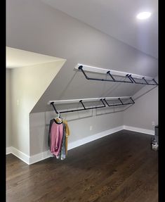 an empty room with some clothes hanging on the wall and a coat rack in the corner