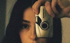 a woman taking a photo with her camera in front of her face and holding it up to the side