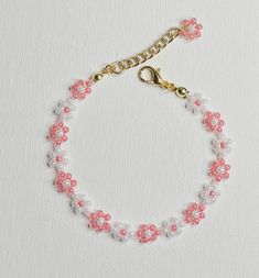 a pink and white beaded bracelet on a gold chain