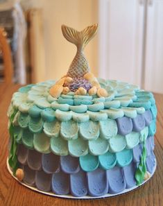 there is a cake that looks like a mermaid on top of the cake, with blue and green icing