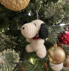 a crocheted dog ornament hanging from a christmas tree with ornaments around it