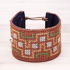 an orange and green woven bracelet sitting on top of a wooden table