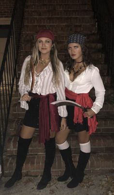 two women dressed in pirate costumes standing next to each other on the stairs at night