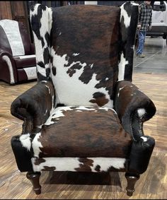 a brown and white chair sitting on top of a hard wood floor covered in cowhide