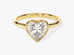 a gold ring with a heart shaped diamond on it's center, set against a white background