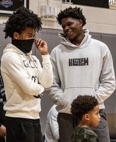 two young men standing next to each other in front of a basketball court with one man covering his face