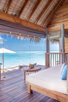 a bed sitting on top of a wooden floor next to the ocean