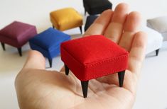 small miniature stools in different colors are being held by a person's hand