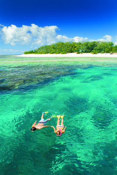 two people are floating in the water near an island