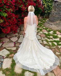 the back of a bride's wedding dress as she walks down a stone path